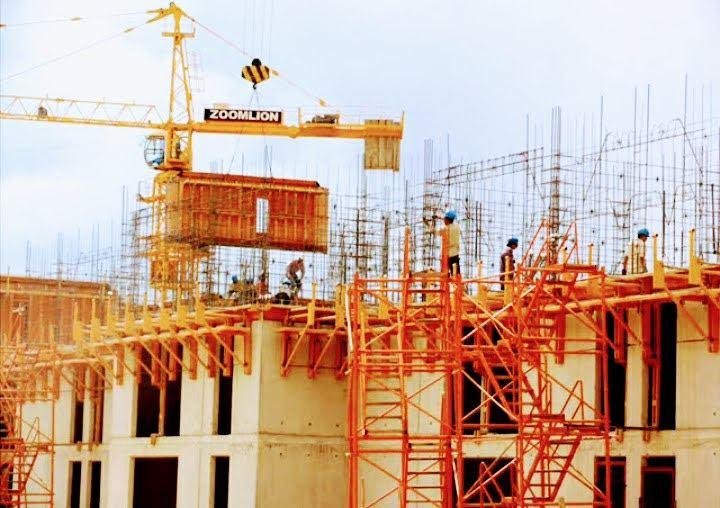 Grúa torre izando encofrado sobre estructura en obra