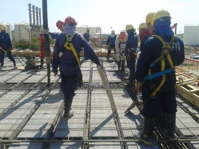 Cuadrilla con arnés trabajando sobre losa armada en instalación industrial